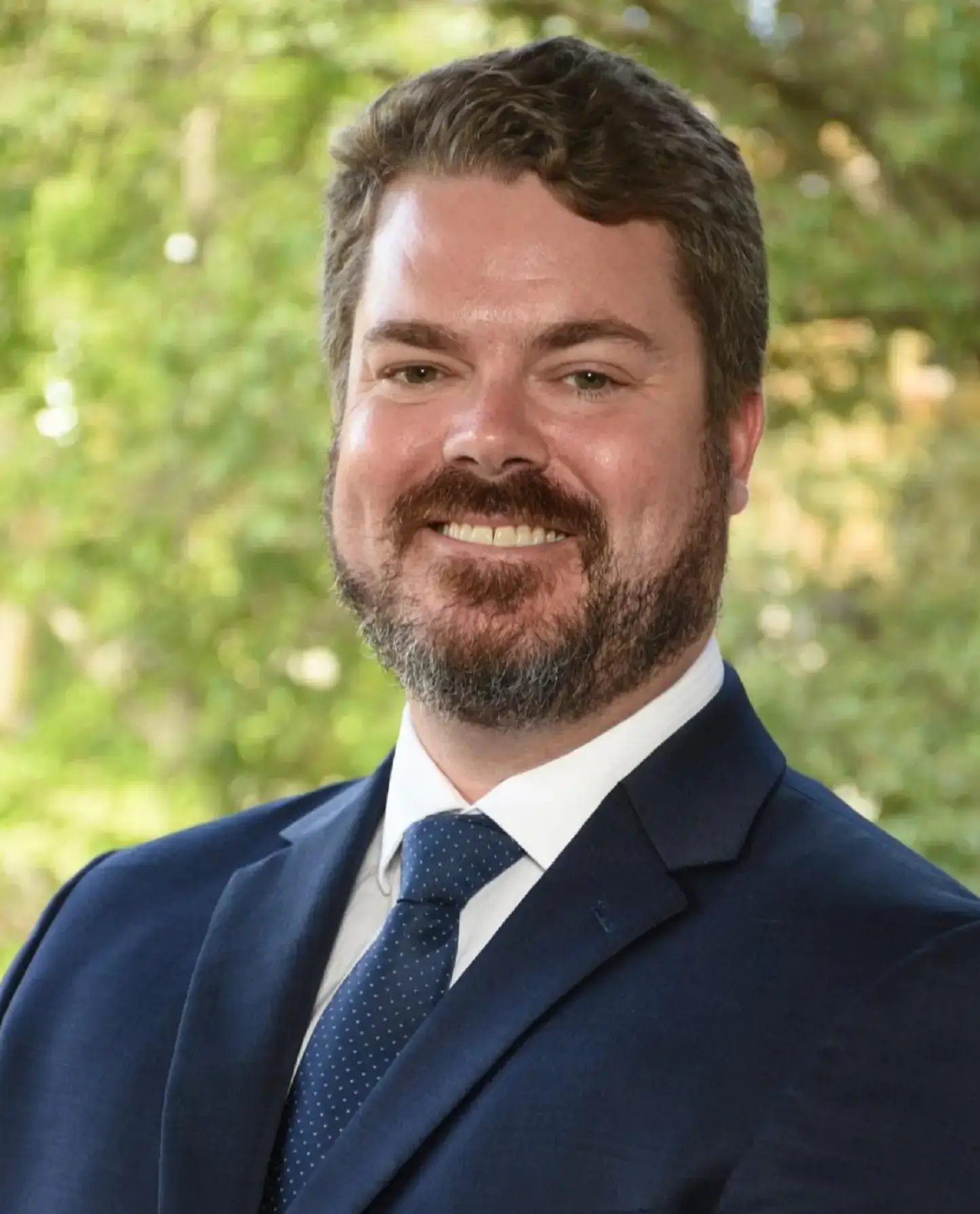 Outdoor headshot of smiling bearded professional